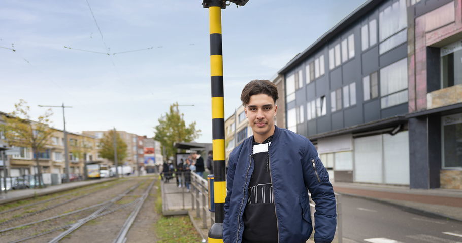 Hamza die aan de tramhalte staat te wachten.